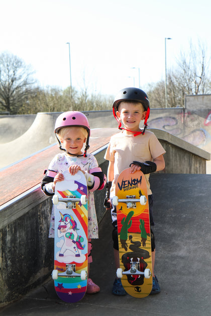 young boy and girl at skatepark holding junior skateboards