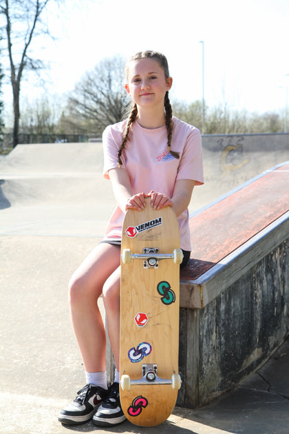 Teen girl at skatepark holding a skateboard
