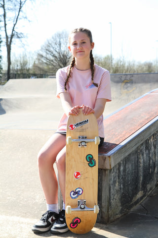 Teen girl at skatepark holding a skateboard